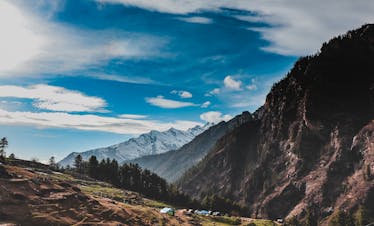 Breathtaking view of the Himalayan mountains in Himachal Pradesh, showcasing lush green forests and clear skies.