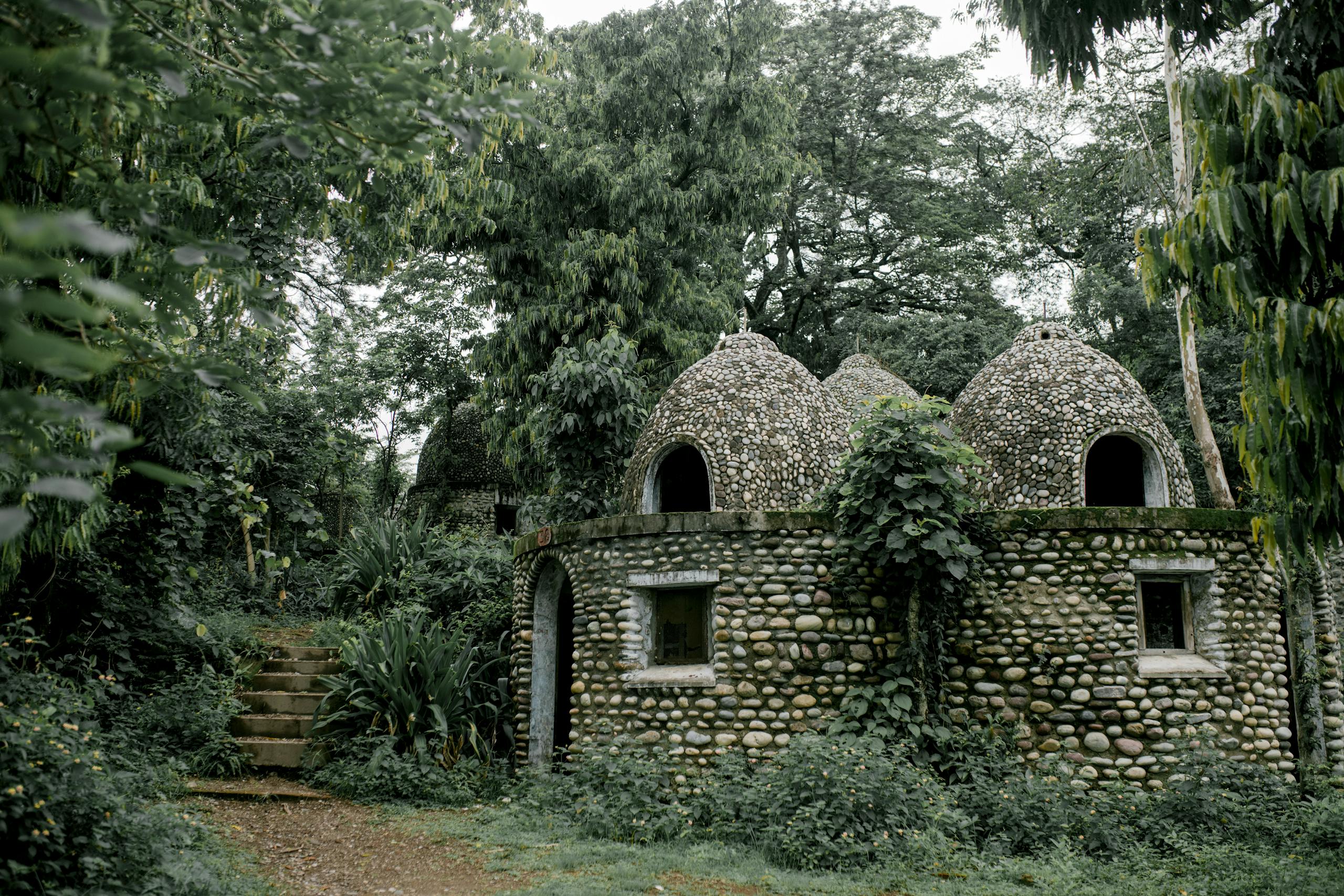 Discover serene stone meditation huts nestled in a lush jungle setting, offering peace and tranquility.